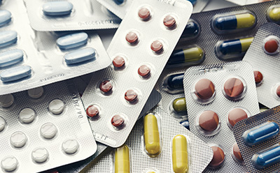 图片展示了各种药丸和胶囊，有多种颜色和大小，包装在重叠的泡罩包装中。