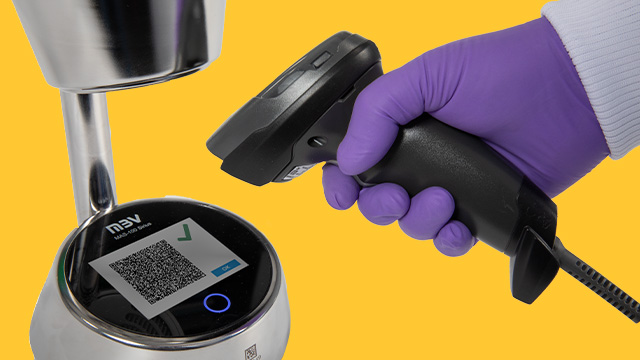 A close-up image of a hand wearing a purple glove holding a barcode scanner aimed at a circular device displaying a QR code. The background is a vibrant blue, enhancing the focus on the scanning action and the technology being used.
