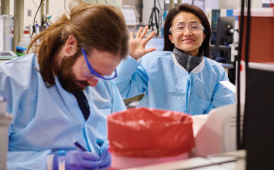 A smiling scientist working together with colleagues in a laboratory setting.