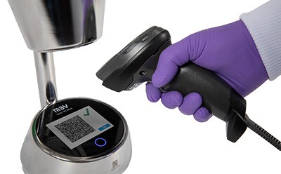 A person in a lab coat using a barcode scanner to scan an air sampling result barcode displayed on a touchscreen, highlighting wireless data transfer capabilities.