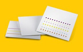 一叠白色的打孔卡片衬托着鲜艳的黄色背景。其中一张打孔卡放在最前面，展示了在不同位置打孔所形成的图案。