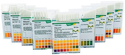 A series of plastic containers with pH indicator strips, arranged in a row. Each container has a label displaying different pH ranges and corresponding color charts for pH testing, with some featuring graphs or additional scientific data. The packaging is primarily green and orange with white text, and each box is designed to dispense the strips for easy access.