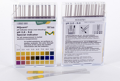 Two clear plastic boxes containing pH indicator strips with a pH range from 2.0 to 9.0. Each box features a color-coded scale on their labels for quick reference. One box is open with several test strips visible in front, alongside additional information and instructions printed on the labels.
