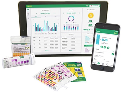 A digital tablet and a smartphone displaying pH measurement and analysis applications, alongside physical pH indicator strips and color charts. The tablet screen shows detailed graphs and statistics, while the smartphone displays a pH reading of 8.5 with a user interface for pH data. The setup illustrates the integration of traditional pH testing methods with modern digital technology for comprehensive analysis.