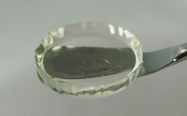 一张特写照片，在一个金属勺盛放的圆形玻璃盘中，整齐地盛放着一种透明的凝胶状物质，这就是水凝胶样品