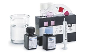 图片展示了一系列实验室设备，包括一个烧杯、两个标有 "M "和 "OH "的化学瓶、一个注射器和 pH 指示条，表明这是一个化学实验室。