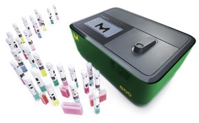 图片显示的是一台绿黑相间的分析机器，可能是分光光度计，前面是一排五颜六色的试管，每个试管都盖上了盖子，贴上了条形码。