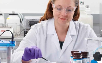 A scientist working at a bench, using tweezers to manipulate a blotting membrane