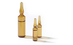 三只大小不一的琥珀色玻璃安瓿，以鲜明的白色为背景。每个安瓿都有一个独特的密封尖端，这是用于保存医疗或化学溶液的容器的特征。
