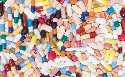 一组形态各异的药片与胶囊。它们呈现出多种形状与色彩，包括粉色、黄色、白色、蓝色和红色。部分胶囊呈透明或不透明状，两端带有不同颜色。