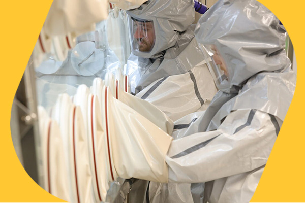 两名穿着防护服的操作员安全处理隔离器中的强效API高效活性药物成分