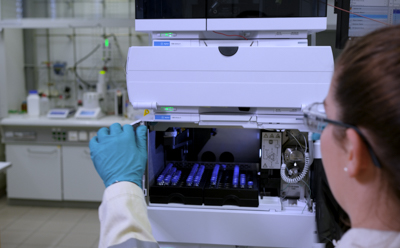 Lab scientist is loading analytical samples into a High-Performance Liquid Chromatography (HPLC) machine for monitoring the progress of chemical syntheses and ensuring the quality of the produced materials.