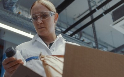 Person in a lab coat examining bottle and packaging materials