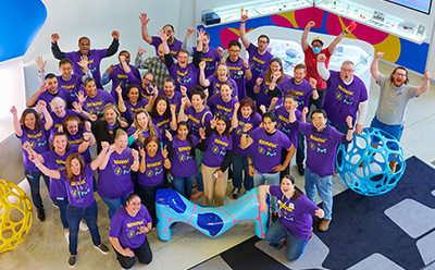 特写图片：墙上贴满了六边形的便条，每张便条上都有孩子们手写的问题和好奇心。这些便条颜色各异，内容包括 "我很想知道...... "等短语，以及关于细菌、海洋和其他有趣话题的问题，营造了一个引人入胜的互动学习环境。