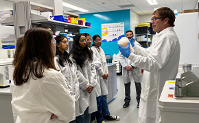 这是 SPARK™ 计划的宣传海报，海报中的小男孩身穿白大褂，戴着安全护目镜，象征着好奇心和科学探索精神。鲜艳的蓝色背景上印有 "好奇心实验 "字样和 SPARK™ 徽标，邀请观众参与动手科学活动。