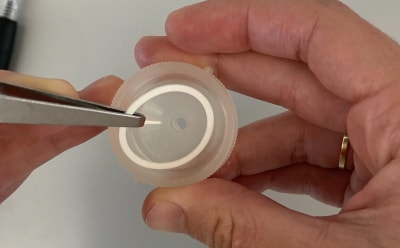 Swinnex<sup>®</sup> Filter Device O-ring Placement Photograph of a person’s hands using forceps to place O-ring within the Swinnex® device.