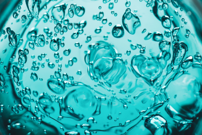 Close-up of clear hydrogels with bubbles in a turquoise liquid, showcasing their texture and transparency