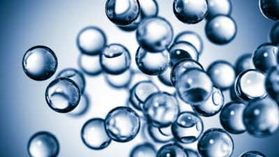 A close-up view of transparent bubbles floating against a soft blue background, creating a sense of depth and movement