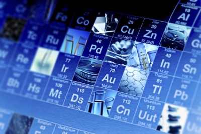 A close-up view of a periodic table featuring various elements, with images representing selected elements, set against a blue background.