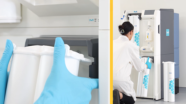 A person in a lab coat and blue gloves is inserting filter cartridges into a laboratory device. The setting features a clean, modern workspace.