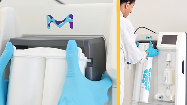 A person in a lab coat and blue gloves is removing a filter cartridge from a laboratory device, showcasing a modern and organized workspace.