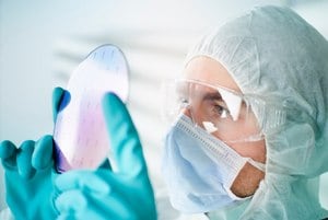 Scientist wearing protective clothing inspecting prefabricated pre-patterned electronic device substrate