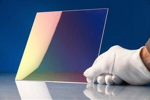 Image of 2-dimensional chalcogenide glass held upright by gloved hand to display the coating.